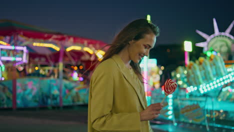 happy girl walking amusement park with lollipop. smiling model resting funfair