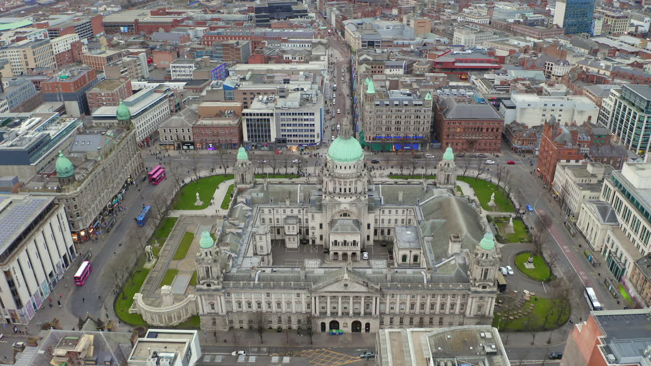 Drone footage tracking forward over Belfast's urban landscape and historic Town Hall