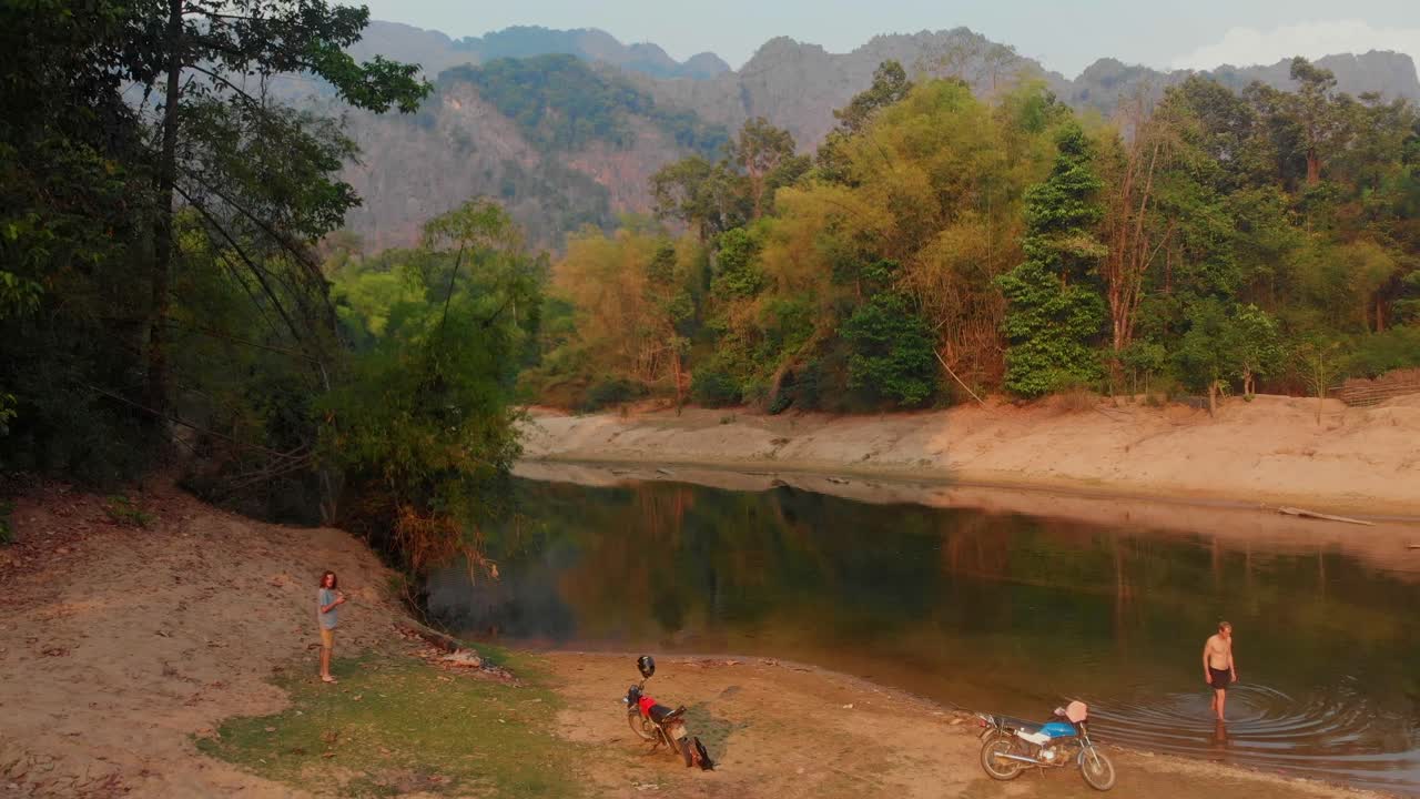 Uomo che nuota nel sereno fiume di Thakhek al tramonto. Laos, Khammouane