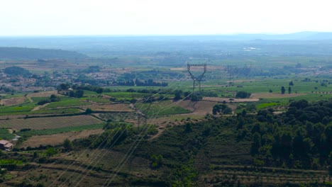 High-aerial-orbiting-shot-of-high-voltage-lines-overhead-vineyards-in-France