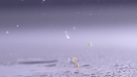 Close-up slowmotion slicing a red paprika pepper with a cleaver on wet table top