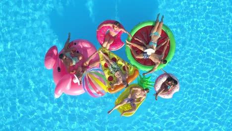 drone: friends chilling on floaties gather together while relaxing at the pool