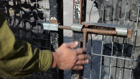 hand of armed israel army soldier closing the gate with metal latch outside