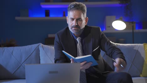 focused businessman carefully reading notebook. he is using the laptop in a serious professional way.