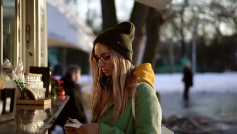 woman in hat taking a change of money from street coffee kiosk in winter