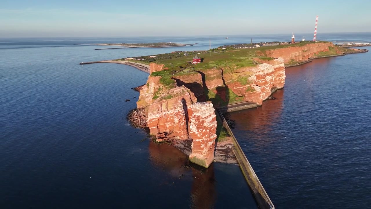 ヘルゴラント島の海岸と、海鳥の営巣地であるランゲ・アンナの赤い崖の夕暮れ時の空撮。