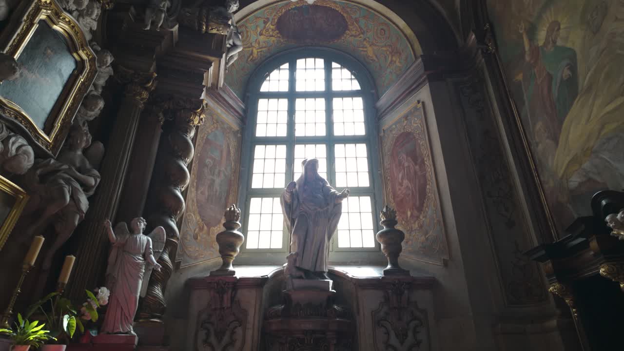 Interior of University Church of the Blessed Name of Jesus in Wrocław, Poland, featuring ornate statues and large arched window