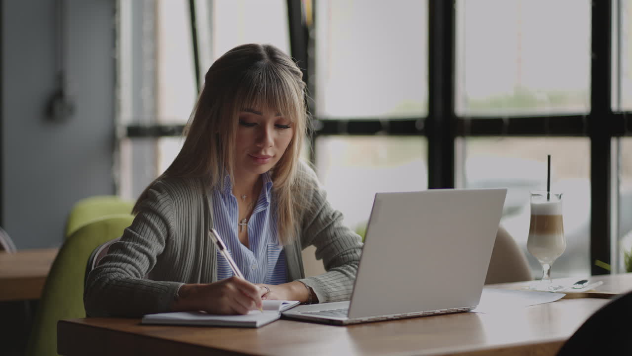 Japanese girl student chances a lecture on a laptop and writes down a notebook
