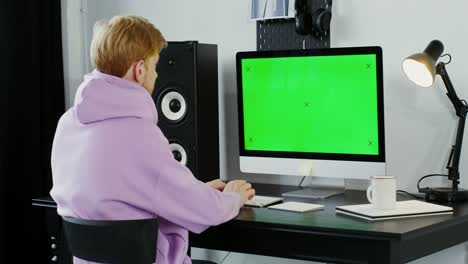 person working on a computer with a green screen