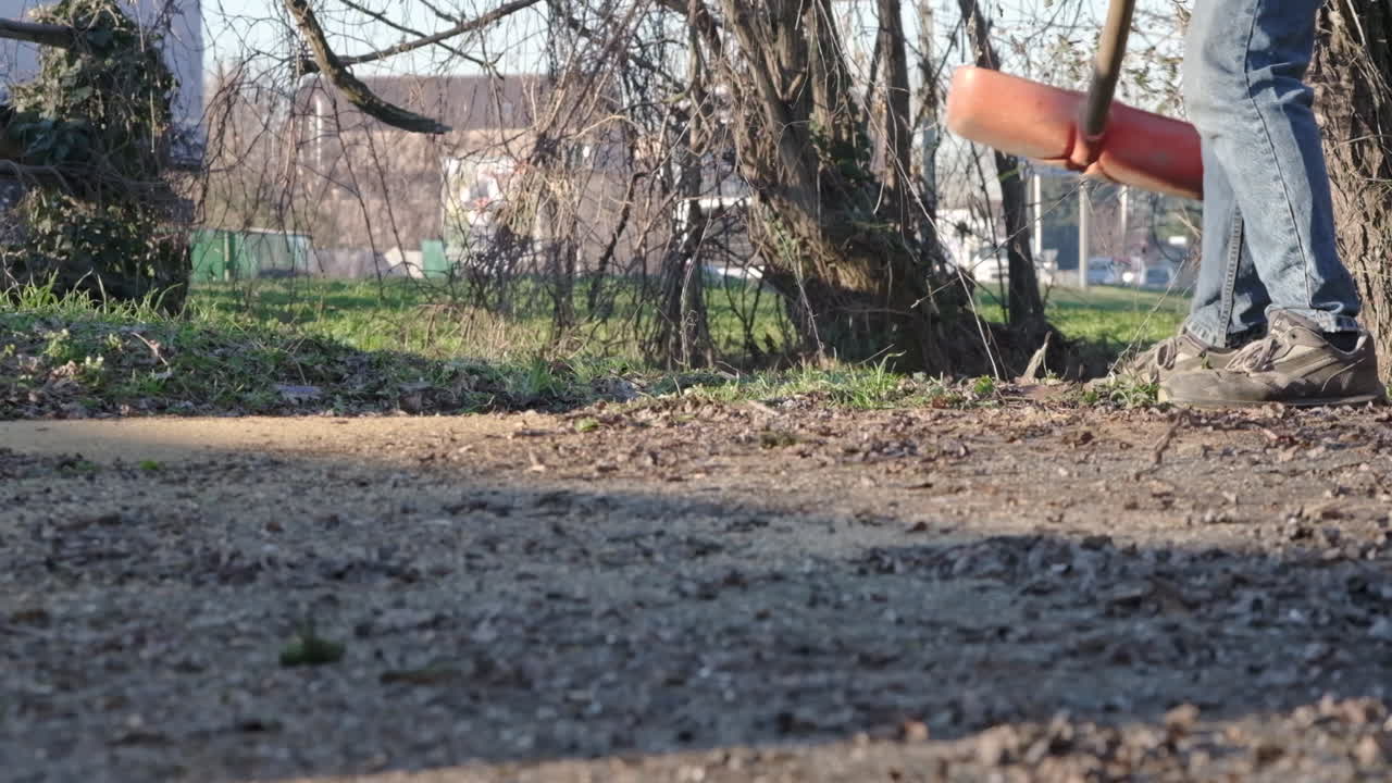 Man Using Red Shovel To Throw Away Leaves At The Garden Near Main Street Outdoors In Cambiago, Northern Italy - slow motion