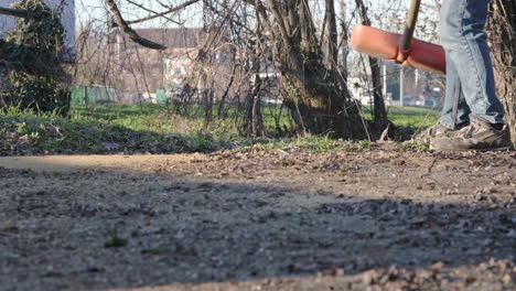 man using red shovel to throw away leaves at the garden near main street outdoors in cambiago, northern italy - slow motion