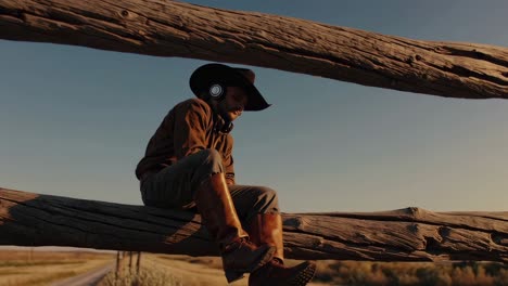 cowboy listening to music on a fence