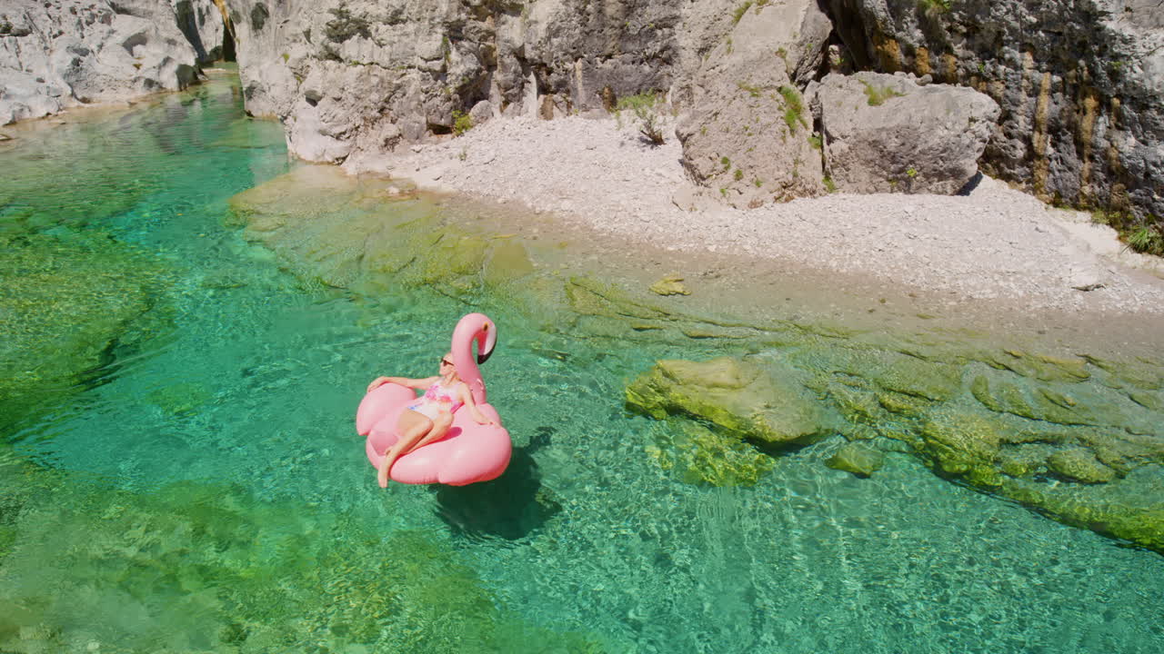 Young woman relaxing on a pink flamingo inflatable