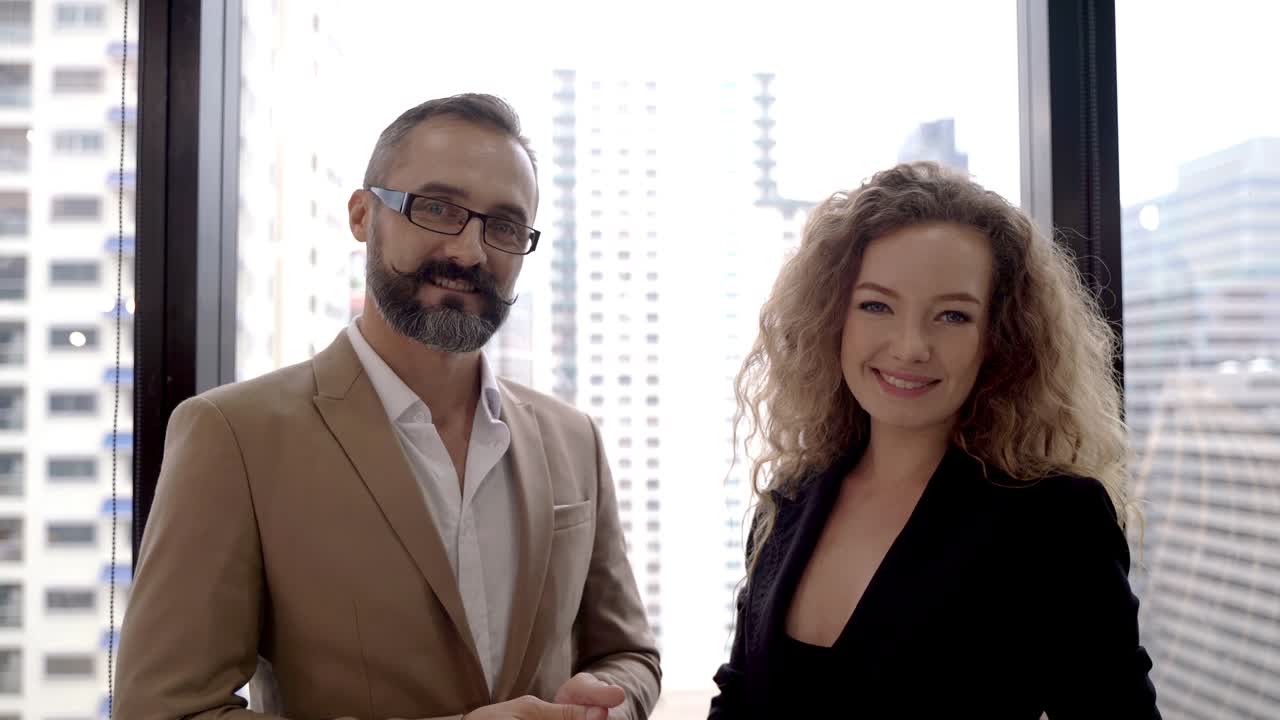 retrato mujer de negocios hablando con un hombre de negocios en la oficina con el edificio exterior a la luz del día. hombre de edad avanzada feliz mirando afuera y sonriendo a la mujer de negocios.