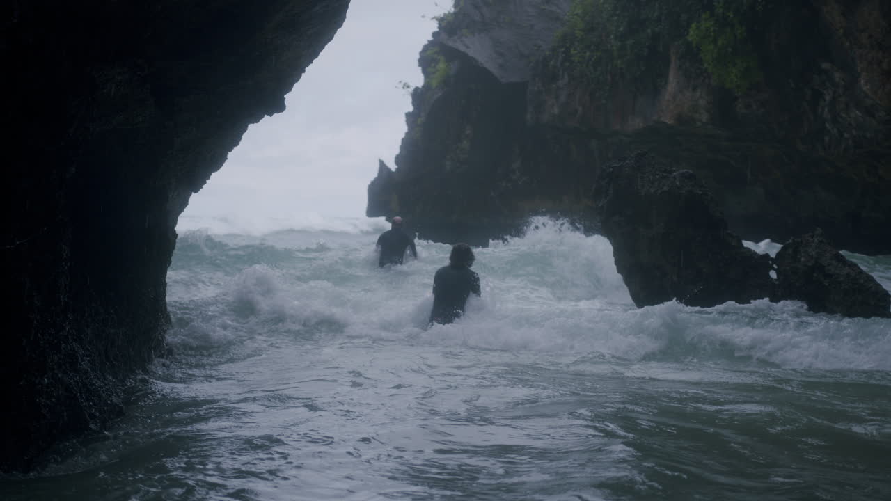 два человека бегут через дикое море, чтобы выжить на бали.