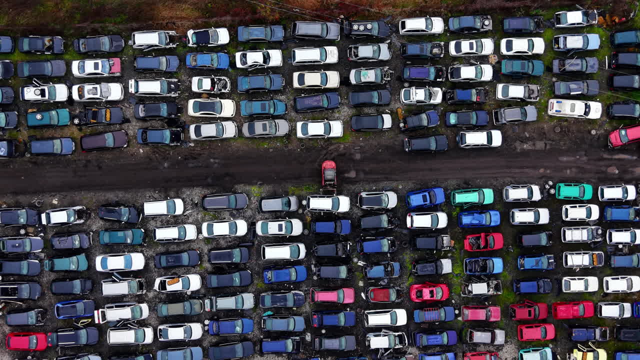 Oude, beschadigde en veelkleurige voertuigen strak opgesteld op een autokerkhof en recyclingcentrum. Bovenaanzicht van geborgen auto's op een schrootplaats.