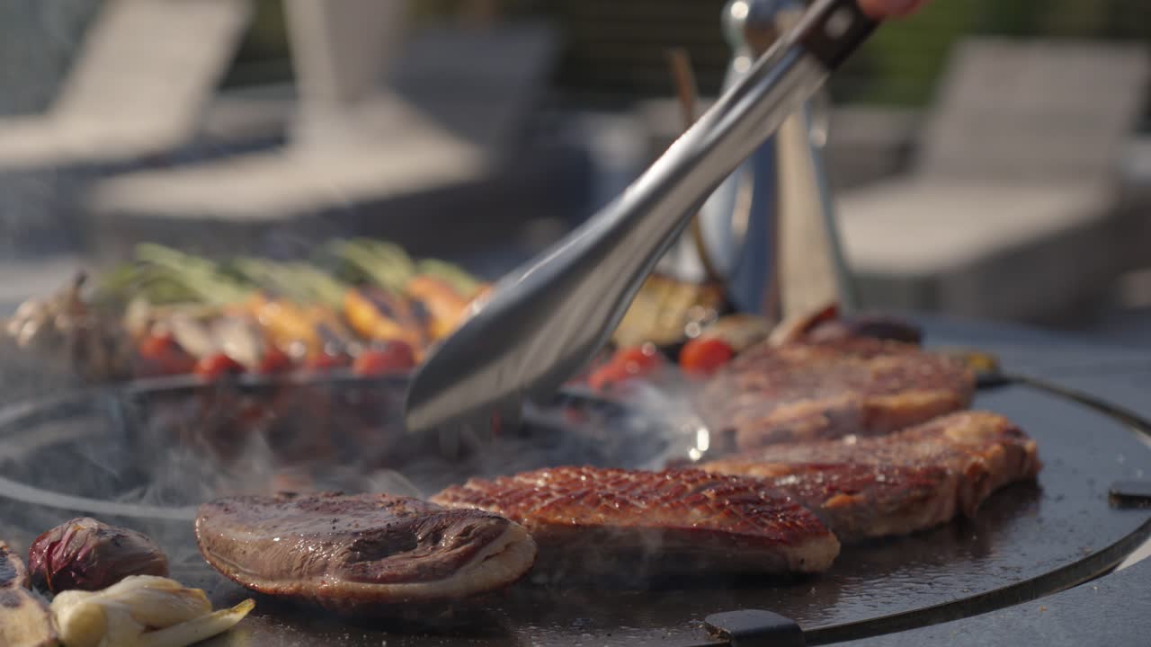 Steaks being flipped with tongs on a barbecueto fully cook through
