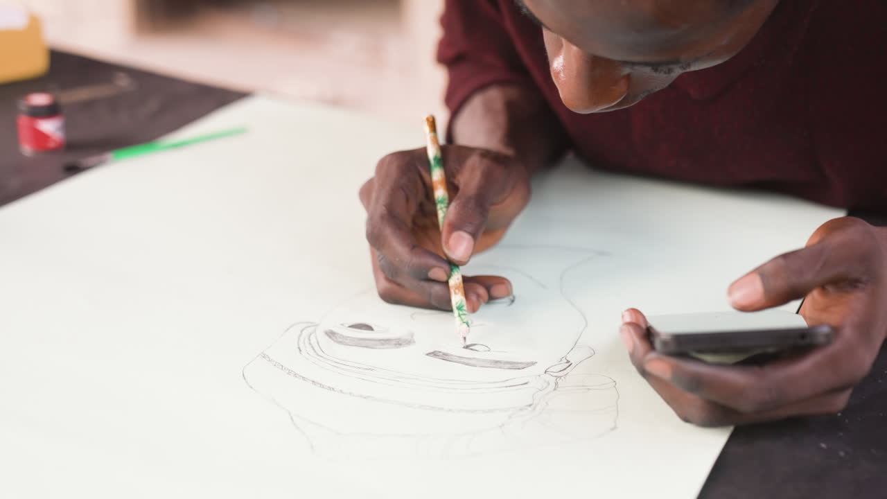 Black artist sketching portrait on paper, closeup hands holding pencil and smartphone reference, dotted outline forming face under warm studio light, focused intimate mood and textured graphite lines