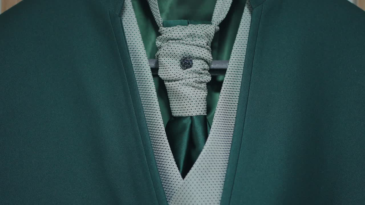 Close up of green suit with light green textured vest and detailed tie knot