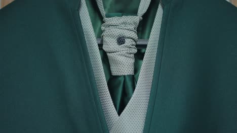 close up of green suit with light green textured vest and detailed tie knot