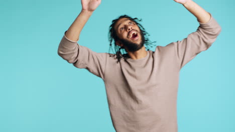 ecstatic person has fun, throwing hands in air, celebrating, studio background