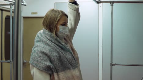 girl in a medical mask standing in a subway car