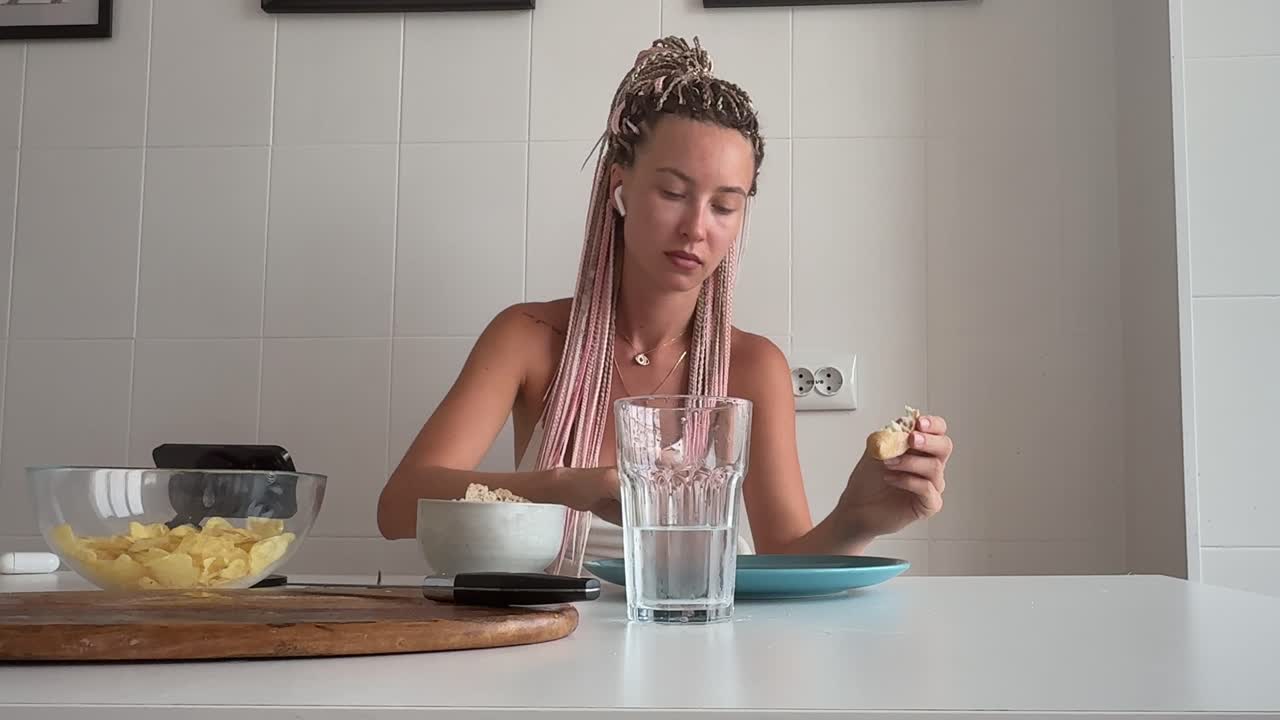 Giovane donna che gusta uno spuntino a base di patatine e salsa in cucina