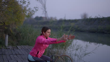 woman exercising and stretching by a river or canal at dusk