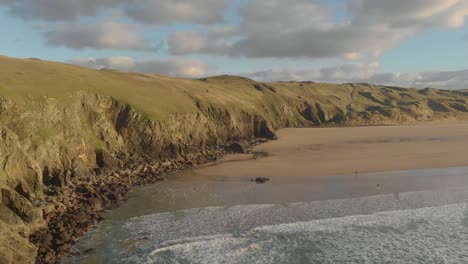 the stunning aerial shot of perran sands during sunset, large cliffs surround the coastline