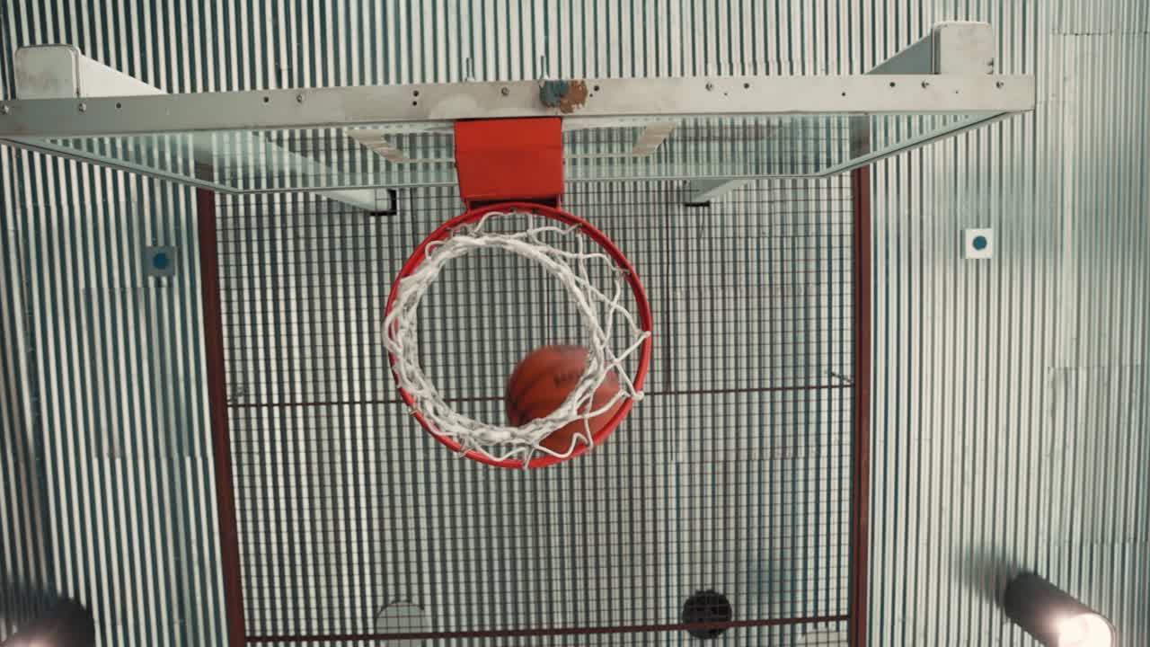 Slow motion footage of a basketball swishing through the hoop in an indoor court