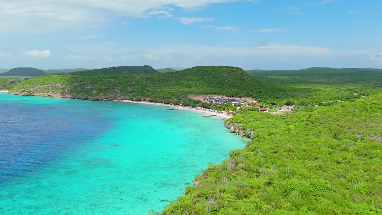 Drönare flyger över Curacaos tropiska, torra landskap medan moln passerar över Playa Porto Mari.