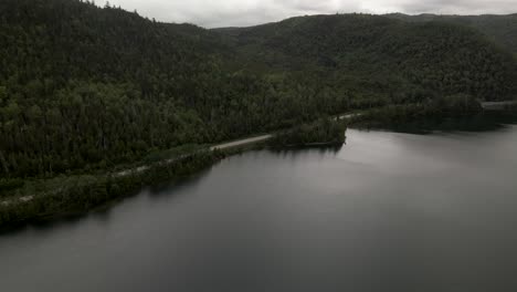 Dramatic-View-Of-The-Lush-Forest-By-The-Lake-In-Gaspesian-Provincial-Park-In-Quebec,-Canada-On-A-Cloudy-Day---aerial-drone