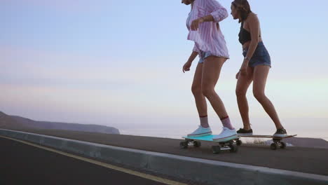 amid a stunning sunset, two friends skateboard on a road, with mountains and a breathtaking sky in the background. slow-motion recording highlights the scene. they sport shorts