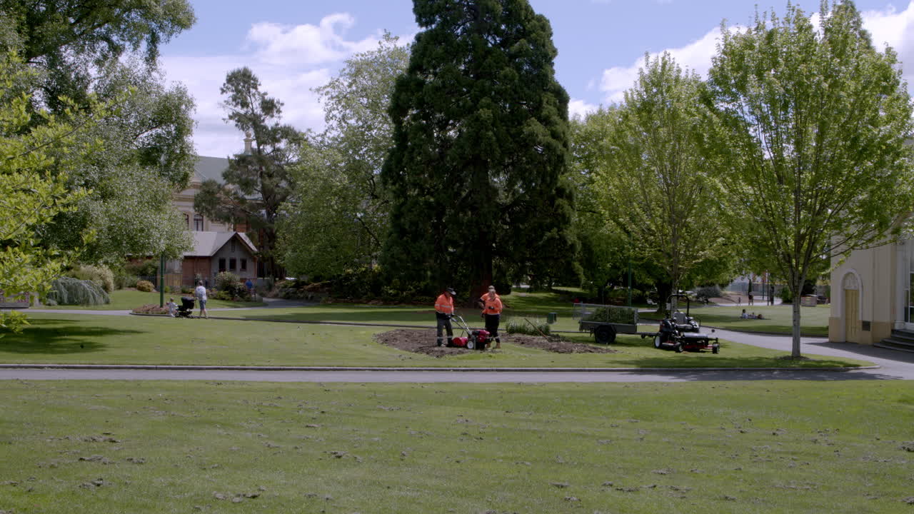 Shot of workers digging a trench for irrigation system installation project in a yard besde a residential street at daytime