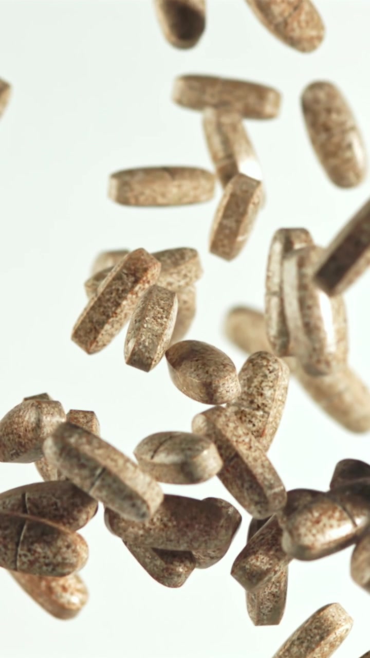 Close-up of Brown Speckled Pills Falling in Slow Motion