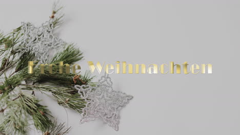 Frohe-Weihnachten-Text-In-Gold-Over-Christmas-Tree-Branch-And-Star-Decorations-On-Grey-Background