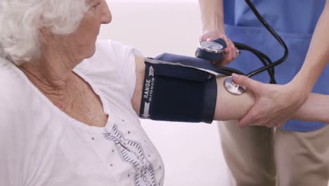 nurse checking bloody pressure of senior woman