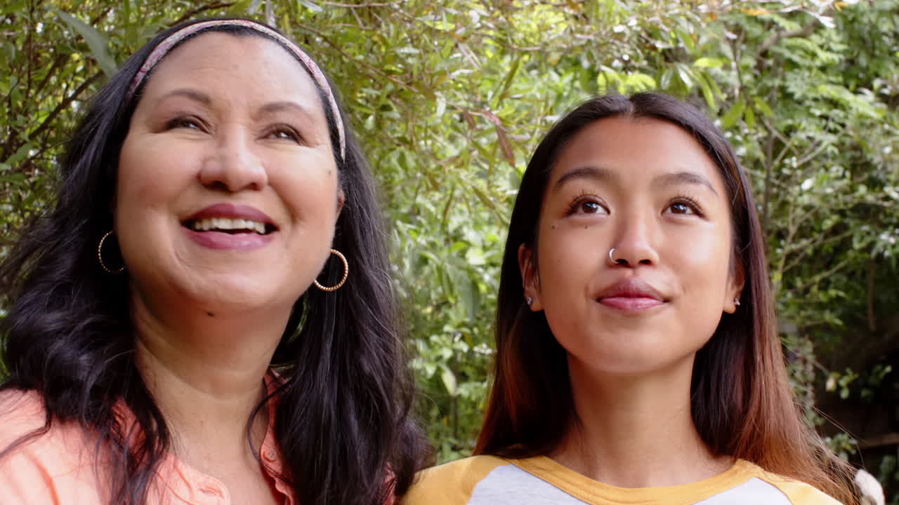 Laughing together in garden, multiracial grandmother and young woman