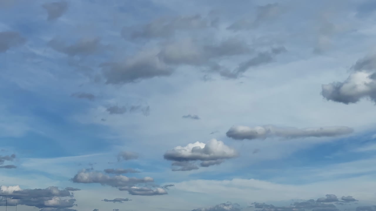 Clouds changing shape in the blue sky. Low angle view at the horizon with floating fluffy clouds. Timelapse.