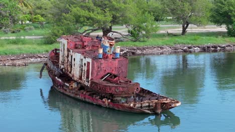 aerial view of old rusty wreck boat at neiba bay with wilderness in background, dominican republic - orbiting shot