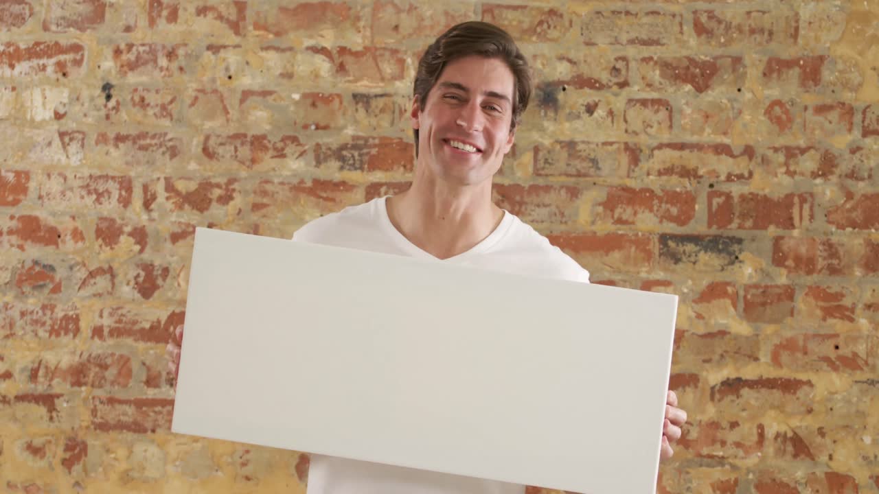 백인 남자 가 벽돌 벽 에  ⁇  직사각형 을 들고 있다