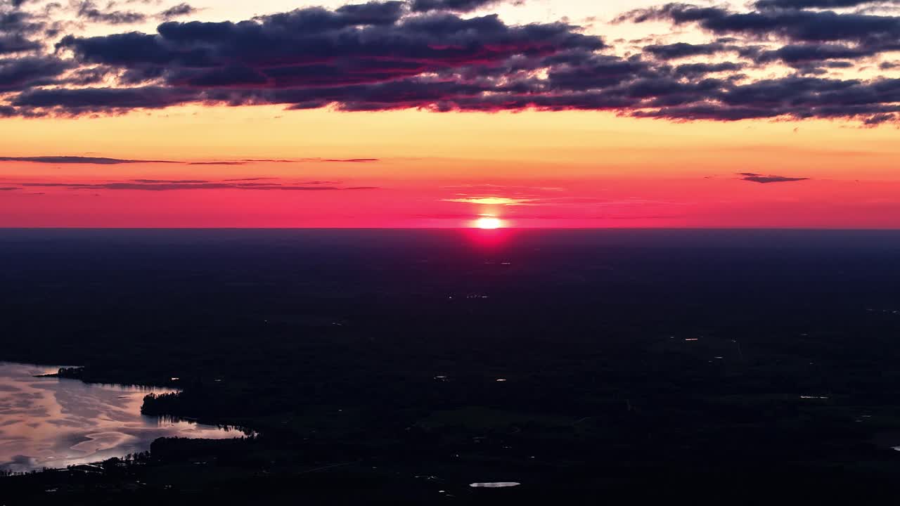Sunset warm last light dusk glow ball dips below silhouette horizon with orange haze