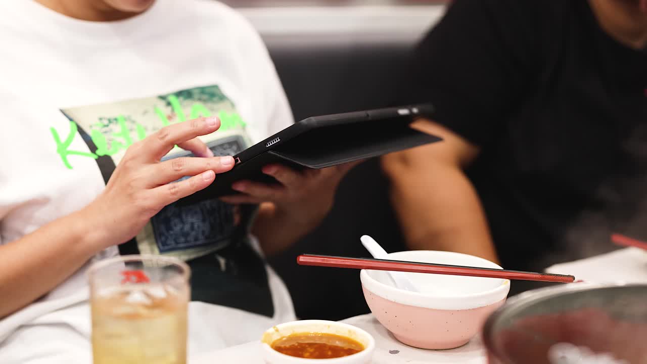 personas que usan una tableta mientras cenan juntas