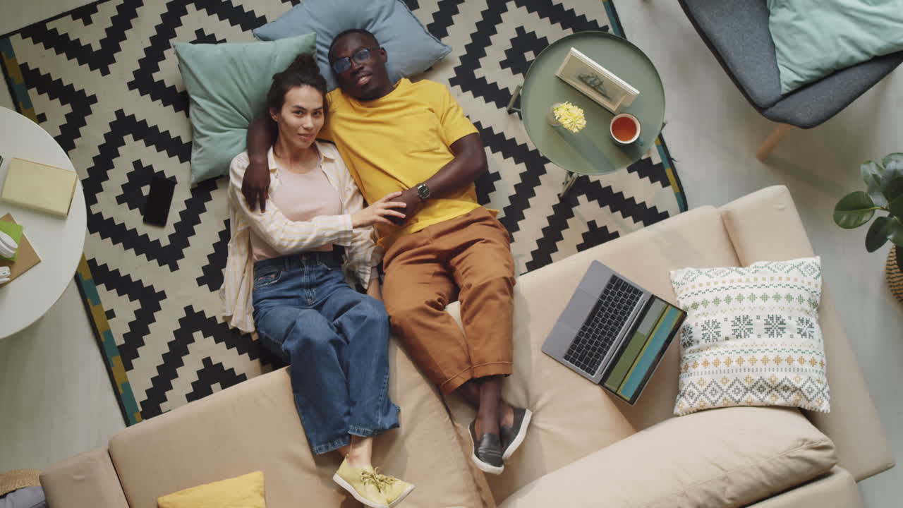 Multiethnic Couple Lying on Floor and Posing for Camera