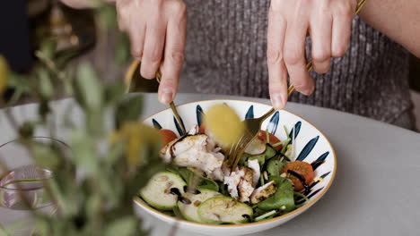 close-up of a person eating a fresh salad with chicken and vegetables