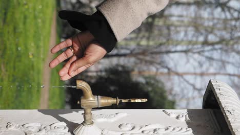 person drinking water from a vintage outdoor fountain in a park