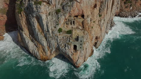 Orbitalluftaufnahme-Des-Historischen-Bergbauhafens-Von-Porto-Flavia-Im-Süden-Sardiniens-Und-Dort,-Wo-Das-Meer-Auf-Die-Klippe-Trifft