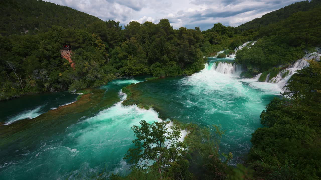 Flowing waterfall cascades with clear water surrounded by forest at Krka National Park, Croatia