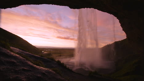 seljalandsfoss waterfall from inside a cave during sunset. iceland