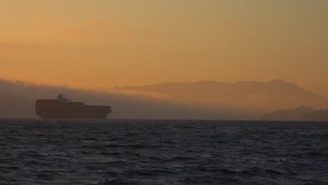 un buque de carga viaja en la distancia a través de alta mar al atardecer 1